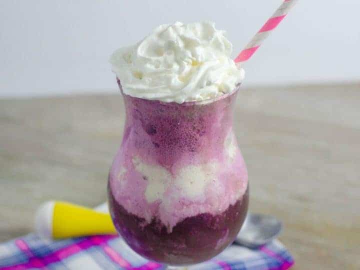 Purple Cow Float in a fancy glass with a straw in it.