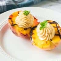 Grilled peaches with cinnamon honey butter on a white plate.