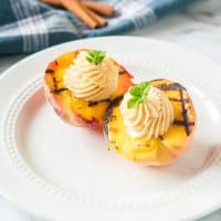 Grilled peaches with cinnamon honey butter on a white plate.