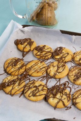 Ritz crackers with peanut butter and chocolate drizzled on them.