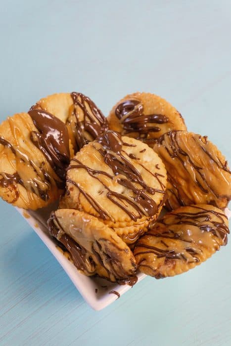 Ritz crackers with peanut butter and chocolate drizzled on them. 