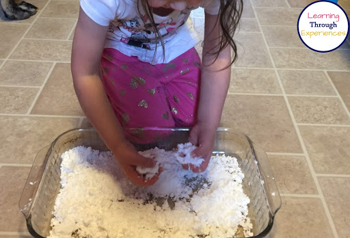 Young girl playing with fake snow in a pyrex baking dish.